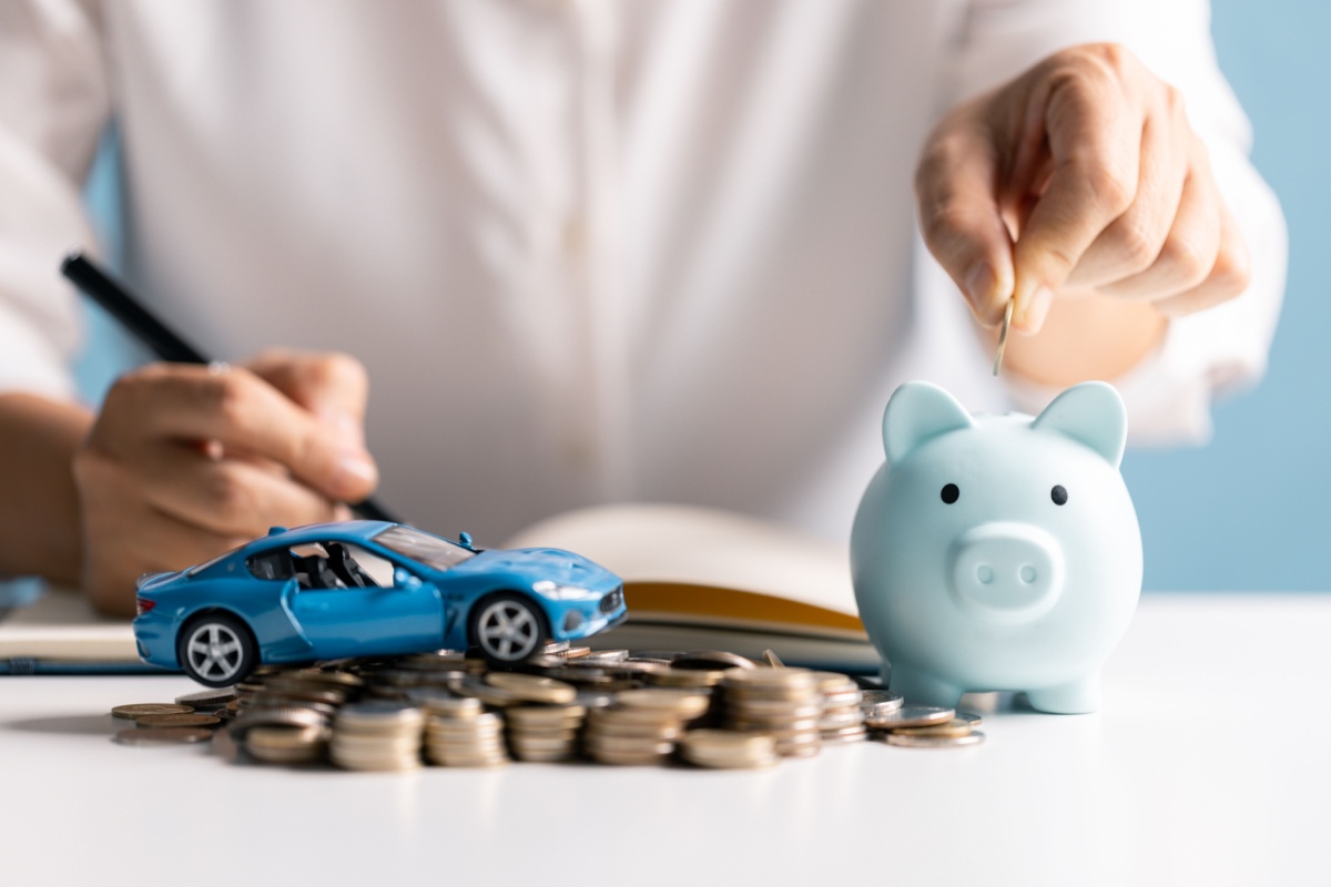 Toy car on money pile next to piggy bank