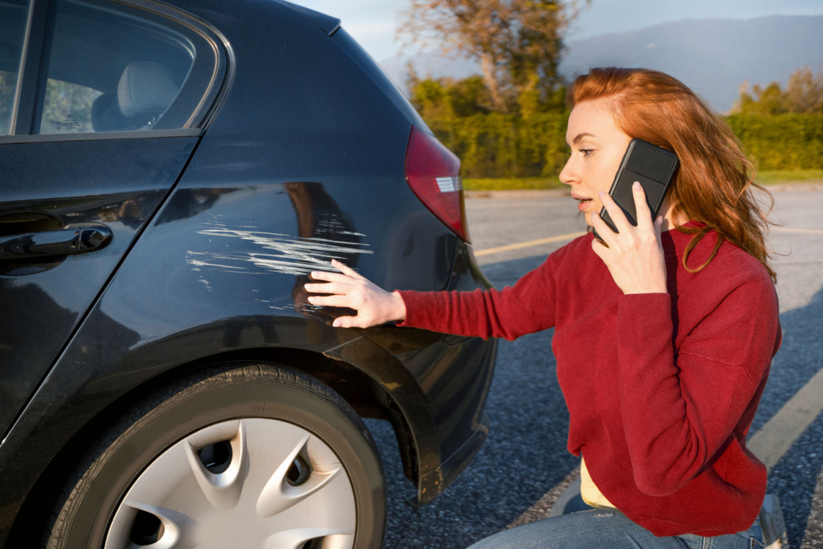 Driver on the phone next to scratched car