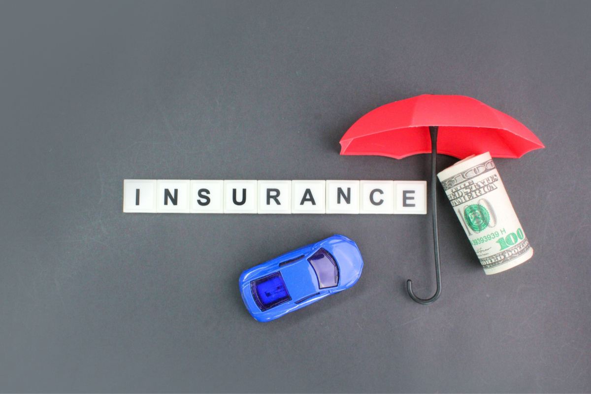 Insurance blocks, toy car, roll of money, and umbrella