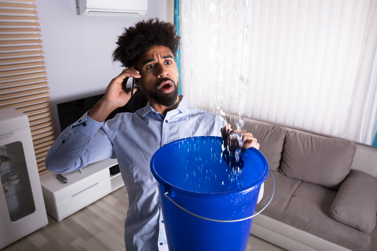 Homeowner holding bucket to roof leak